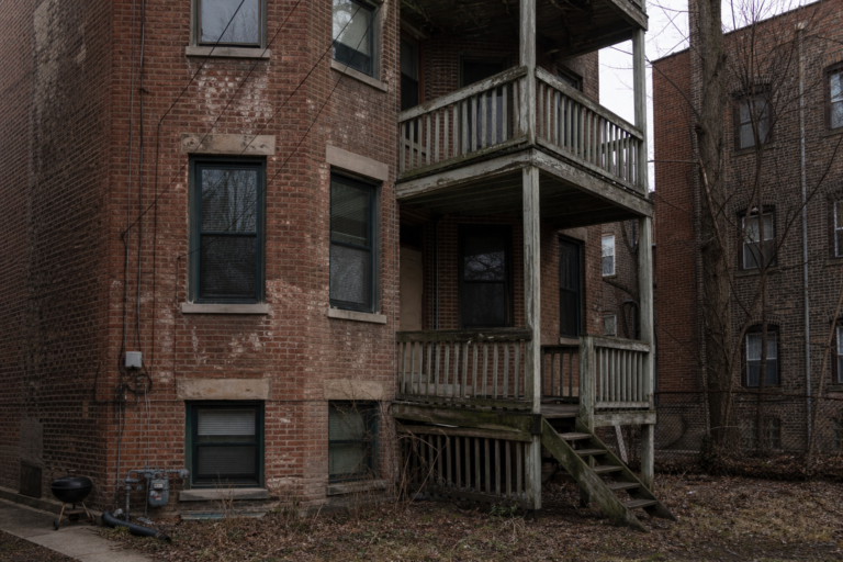 The weathered brick exterior and sagging back porch of an older Chicago apartment building