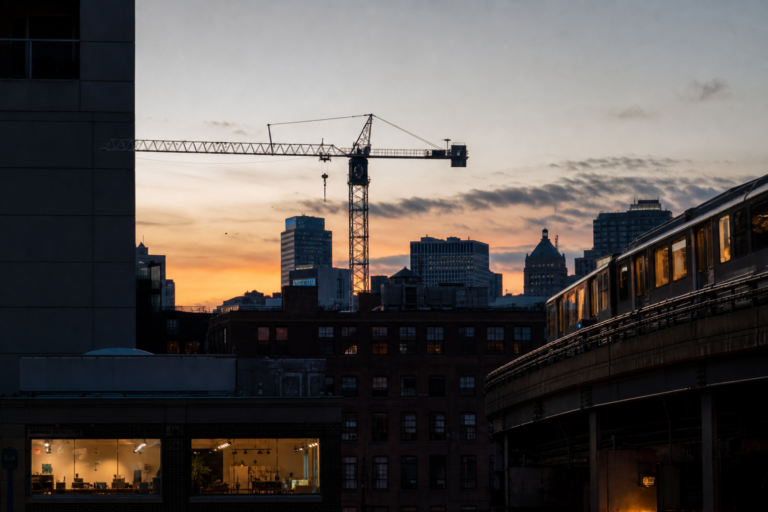 Layered dusk scene of a construction crane, lit storefront, and elevated track