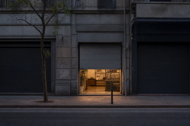 Storefront with security gate half-raised on a quiet retail street at morning