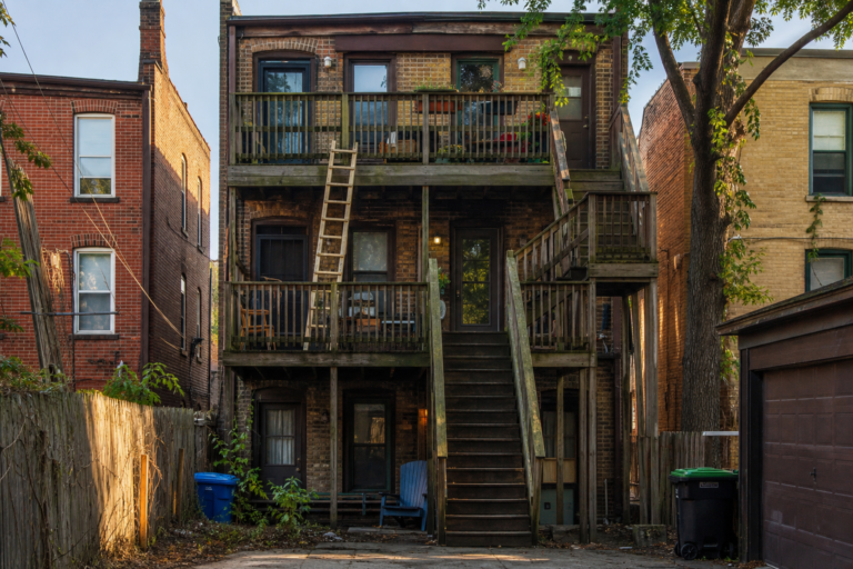 Wooden porch and exterior stairs on a Chicago brick three-flat, seen from the alley