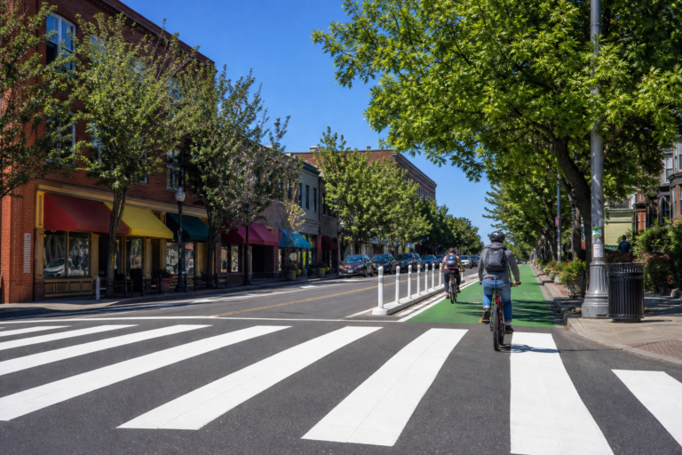 A protected bike lane and crosswalk on a sunny city street