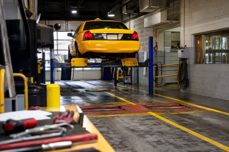 A taxi raised on a lift in a municipal inspection garage bay