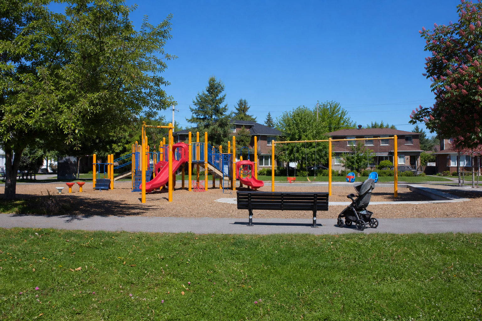A colorful suburban playground with a stroller by a bench on a sunny morning