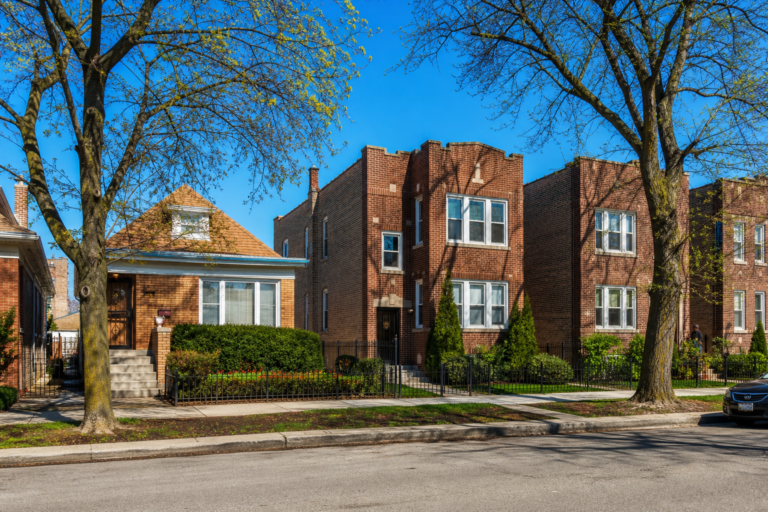 Brick workers' cottages and two-flats with small front gardens on a level street