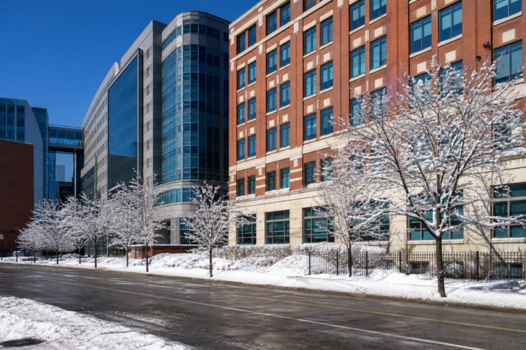 Brick and glass hospital buildings along a snowy Chicago street on a bright winter day