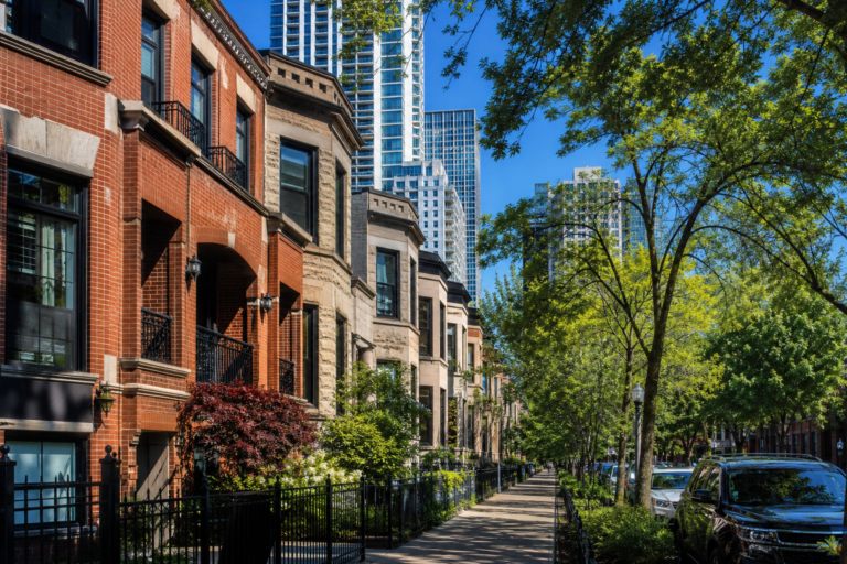 Brick and limestone rowhouses on a level street with condominium towers rising behind them