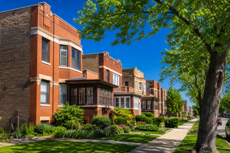 Brick two-flats and three-flats with enclosed front porches on a level, tree-lined street